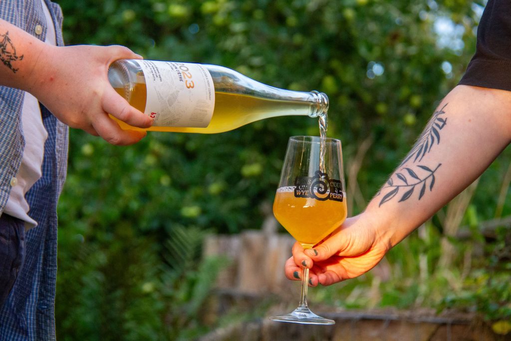 Picture of someone pouring cider into branded wine glass