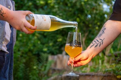 Picture of someone pouring cider into branded wine glass