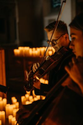 Photo of violinist surrounded by candles